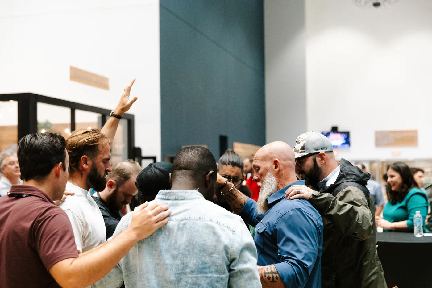 A group praying together with hands resting on one another’s shoulders in a church